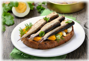 Geräucherte Fische mit Salat auf einem Baguette.