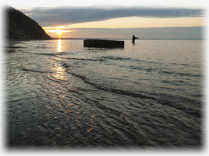 Abend am Meer mit Steinen, die aus dem Wassser ragen.