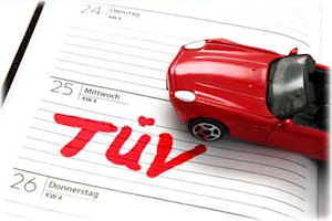 Ein Modellauto steht auf einem Notizbuch, auf dem TÜV steht