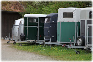 Verschiedene Pferdeanhänger auf einem Hof.