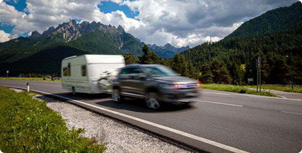 Mit unseren günstigen Tarifen sparen Sie sich eine Menge Zeit und Geld. Wohnwagen vor einer Skyline.